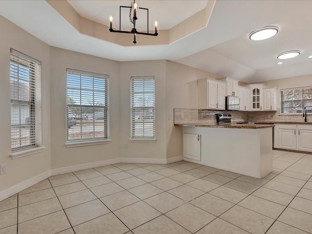 kitchen with a raised ceiling, white cabinets, electric stove, light stone countertops, and backsplash