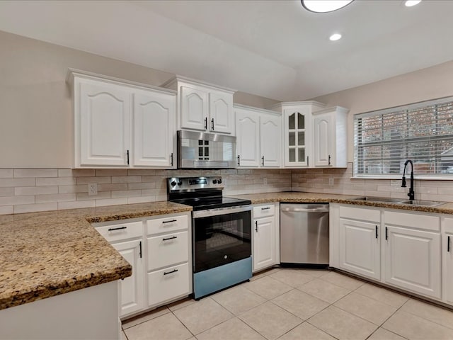 kitchen featuring sink, tasteful backsplash, light stone counters, appliances with stainless steel finishes, and white cabinets