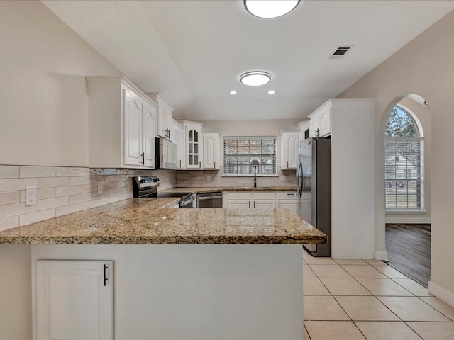 kitchen with light tile patterned floors, a wealth of natural light, stainless steel appliances, and kitchen peninsula