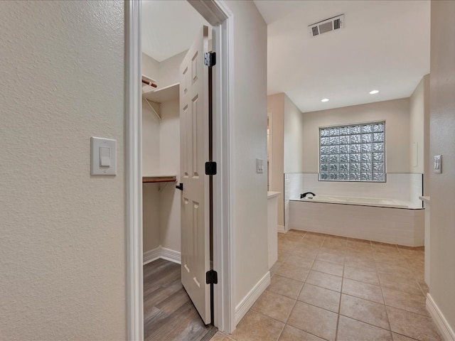 bathroom featuring a relaxing tiled tub and tile patterned floors