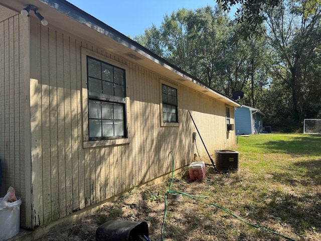 view of side of property with central air condition unit and a yard