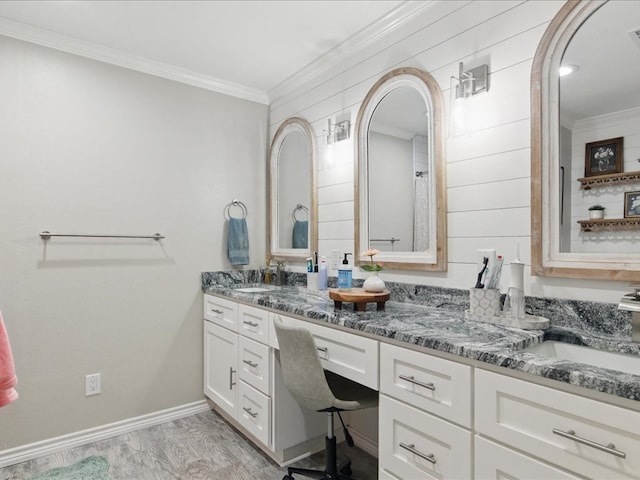 full bath featuring double vanity, baseboards, ornamental molding, and a sink