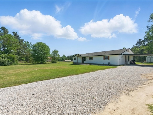 single story home featuring gravel driveway, a front lawn, and an attached carport