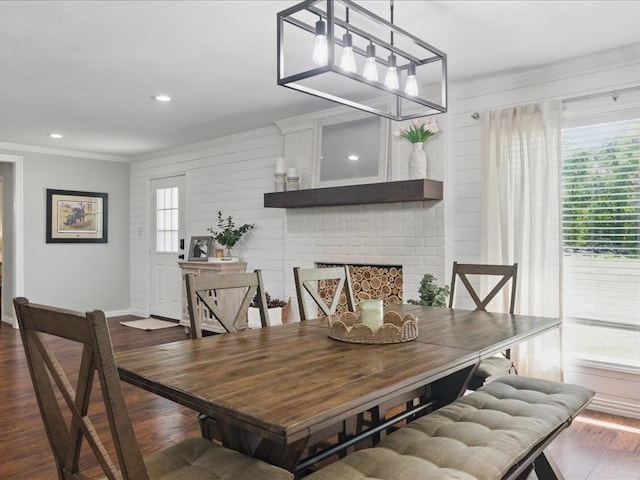 dining area featuring a fireplace, dark wood-style flooring, ornamental molding, and baseboards