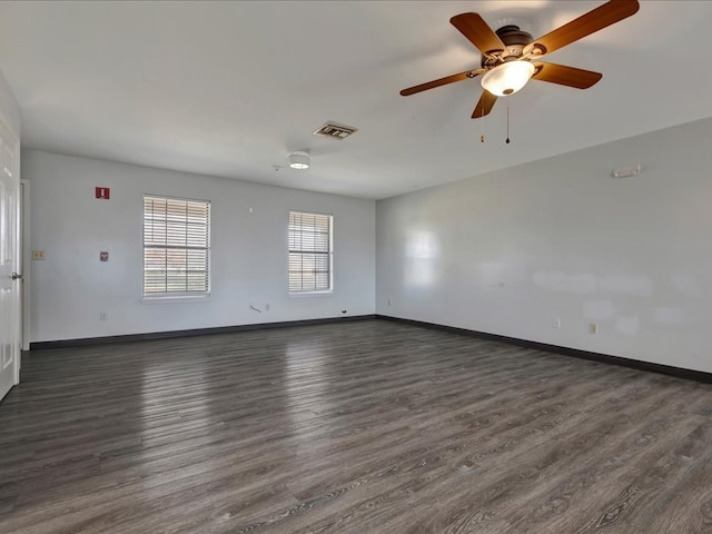 unfurnished room with visible vents, baseboards, and dark wood-style flooring