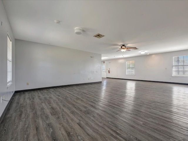 unfurnished room featuring dark wood-style floors, a wealth of natural light, and baseboards