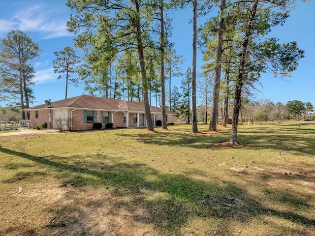 view of front of property with driveway, brick siding, an attached garage, and a front yard