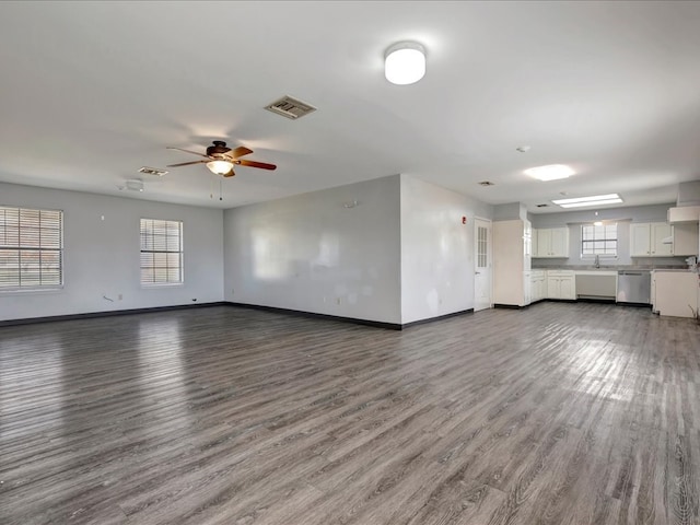 unfurnished living room with visible vents, a ceiling fan, a sink, wood finished floors, and baseboards