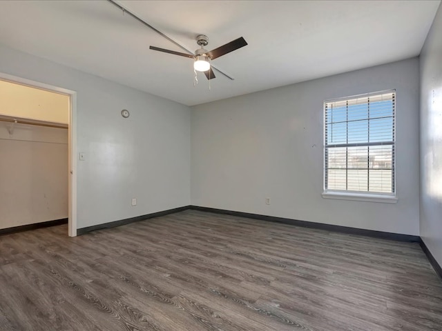 unfurnished bedroom featuring a closet, ceiling fan, baseboards, and dark wood-style flooring