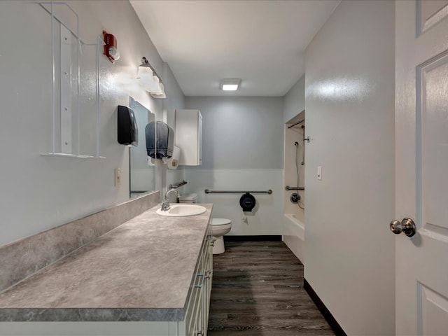 bathroom featuring baseboards, toilet, shower / tub combination, wood finished floors, and vanity