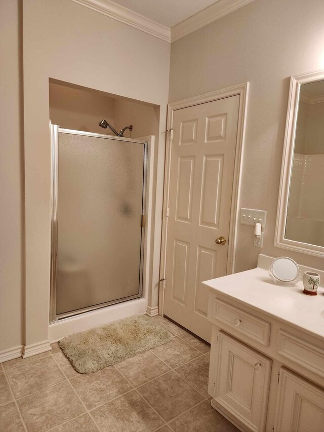 bathroom featuring tile patterned flooring, ornamental molding, vanity, and a shower with shower door