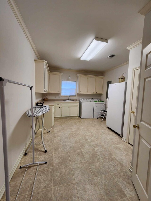 kitchen featuring ornamental molding, sink, cream cabinets, white refrigerator, and washing machine and clothes dryer