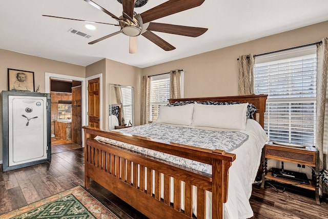 bedroom with dark wood-type flooring, ceiling fan, and ensuite bath