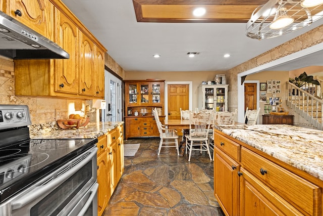 kitchen featuring tasteful backsplash, extractor fan, light stone countertops, and range with two ovens