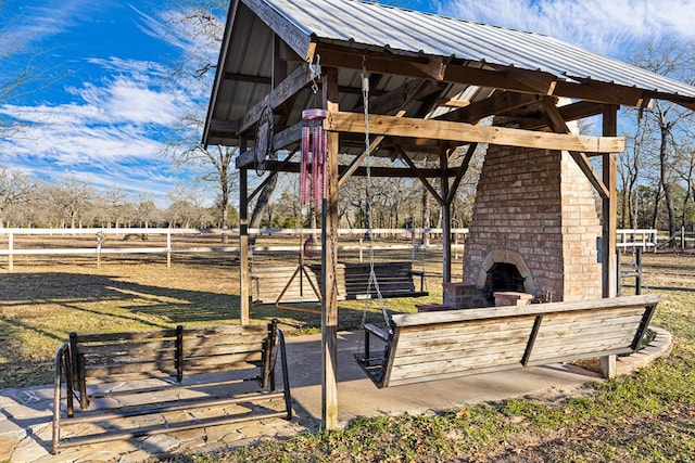 view of patio featuring an outdoor brick fireplace and a rural view