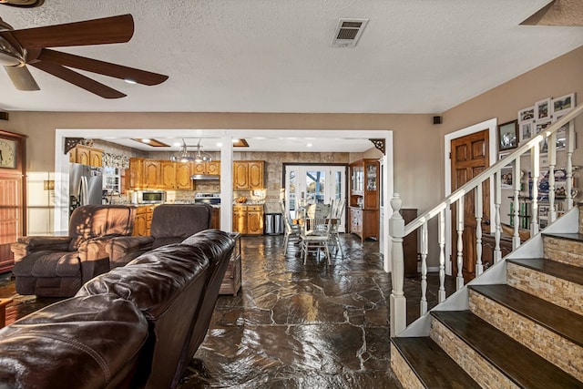 living room featuring ceiling fan and a textured ceiling