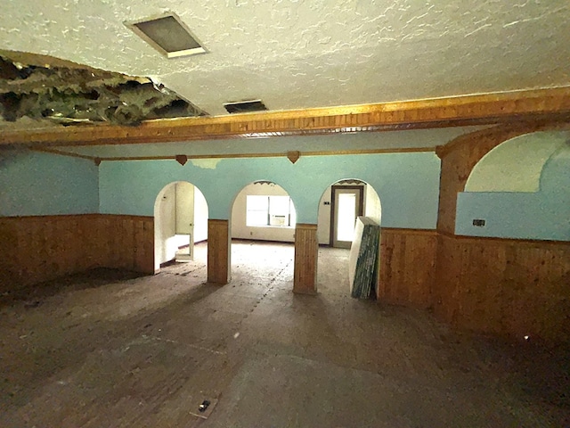 interior space with wood walls, wainscoting, and a textured ceiling