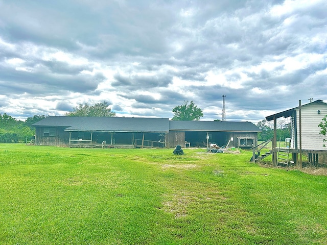 rear view of property featuring a pole building, an outdoor structure, and a lawn