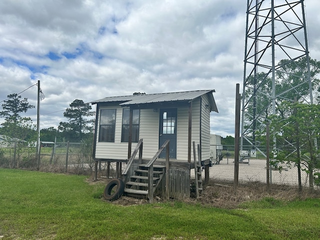 view of front of property featuring metal roof, fence, and a front lawn
