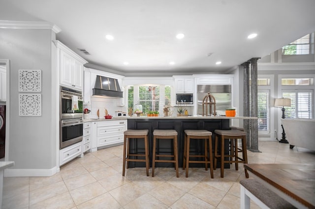486 Brookwood Dr, Diboll, TX 75941 - kitchen with wall chimney range hood, built in appliances, decorative backsplash, a kitchen island, and visible vents