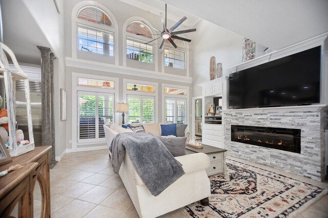486 Brookwood Dr, Diboll, TX 75941 - living room featuring a glass covered fireplace, a towering ceiling, light tile patterned flooring, baseboards, and a ceiling fan