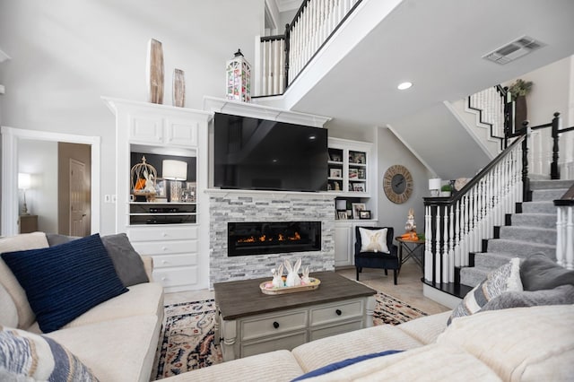 486 Brookwood Dr, Diboll, TX 75941 - living area with a stone fireplace, visible vents, built in features, high vaulted ceiling, and stairs