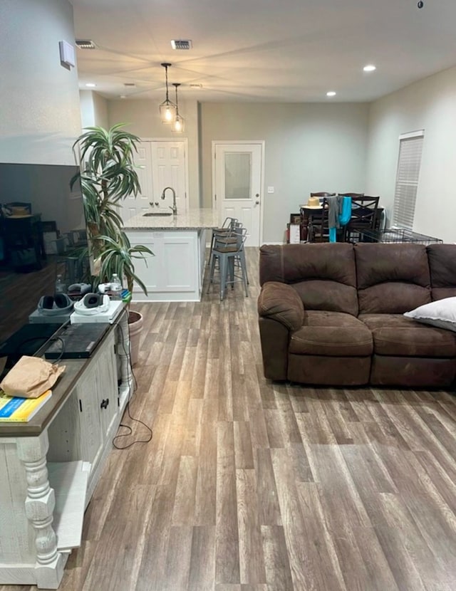 living room with light wood finished floors, visible vents, and recessed lighting