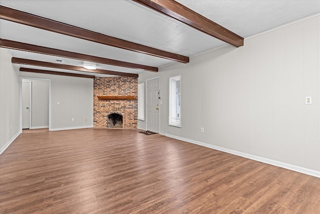 unfurnished living room with a fireplace, hardwood / wood-style floors, a textured ceiling, and beamed ceiling