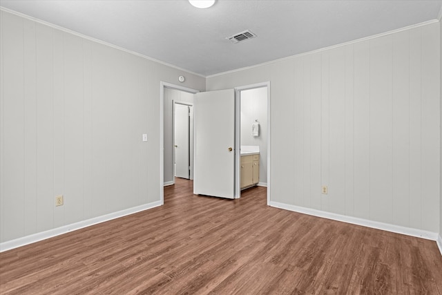 unfurnished bedroom with hardwood / wood-style flooring, crown molding, and wooden walls