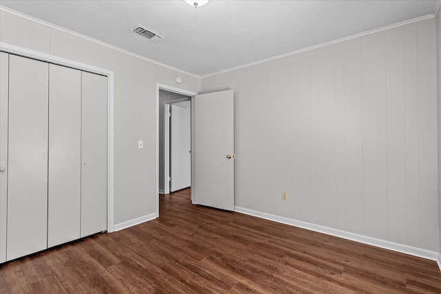 unfurnished bedroom with dark hardwood / wood-style flooring, a closet, and ornamental molding