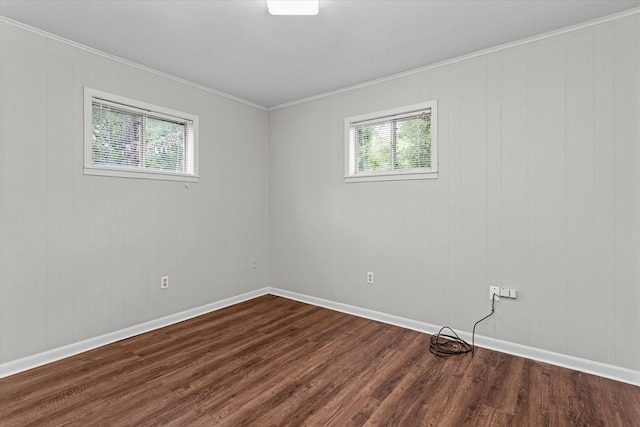 empty room with plenty of natural light, wood walls, dark hardwood / wood-style flooring, and ornamental molding