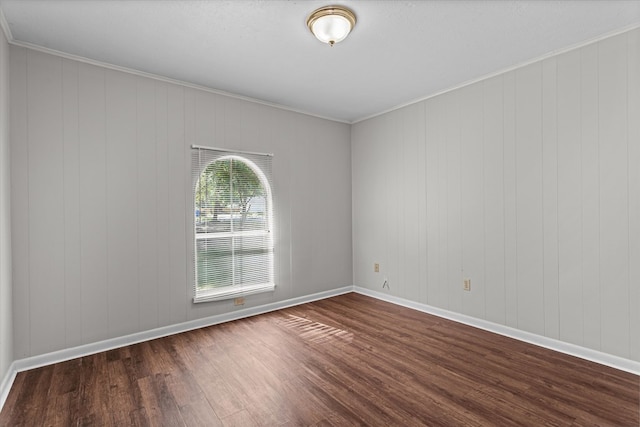 empty room featuring wood walls, dark wood-type flooring, and ornamental molding