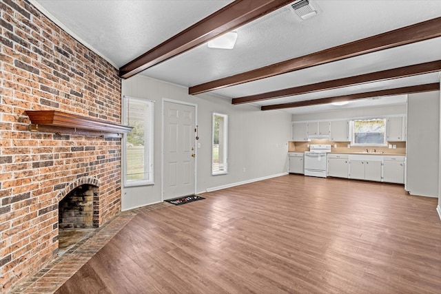 unfurnished living room with wood-type flooring, a textured ceiling, and a brick fireplace