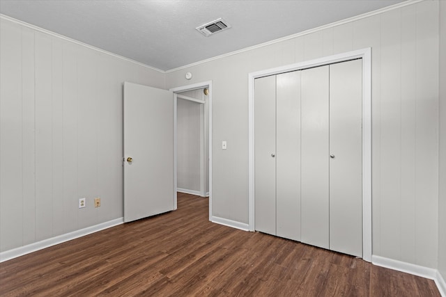 unfurnished bedroom featuring dark hardwood / wood-style flooring, ornamental molding, a textured ceiling, and a closet