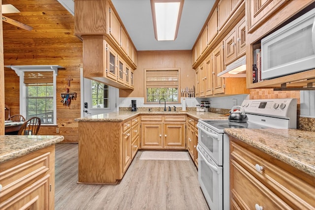 kitchen featuring plenty of natural light, light wood-type flooring, white appliances, and wooden walls