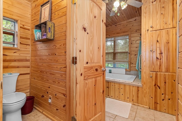 bathroom featuring a washtub, toilet, ceiling fan, and wooden walls