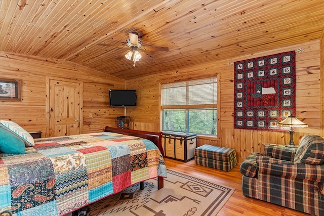 bedroom featuring ceiling fan, wooden ceiling, light hardwood / wood-style flooring, vaulted ceiling, and wooden walls