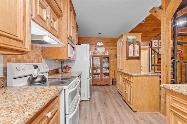 kitchen featuring light stone countertops, light hardwood / wood-style flooring, decorative light fixtures, white appliances, and wooden walls