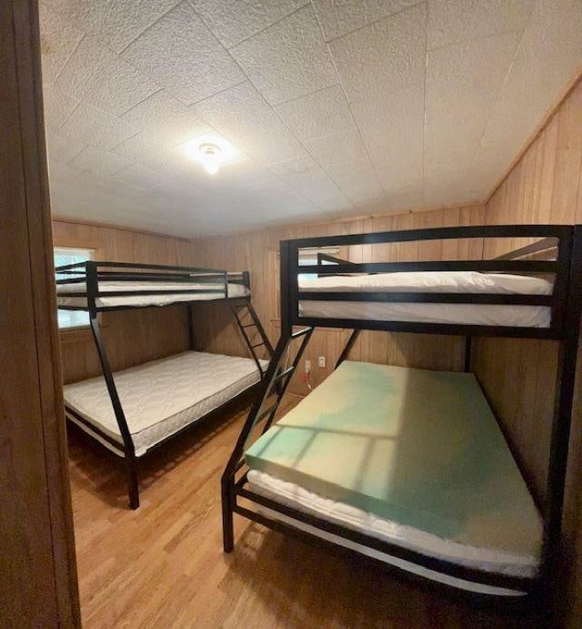 bedroom featuring hardwood / wood-style flooring and wooden walls