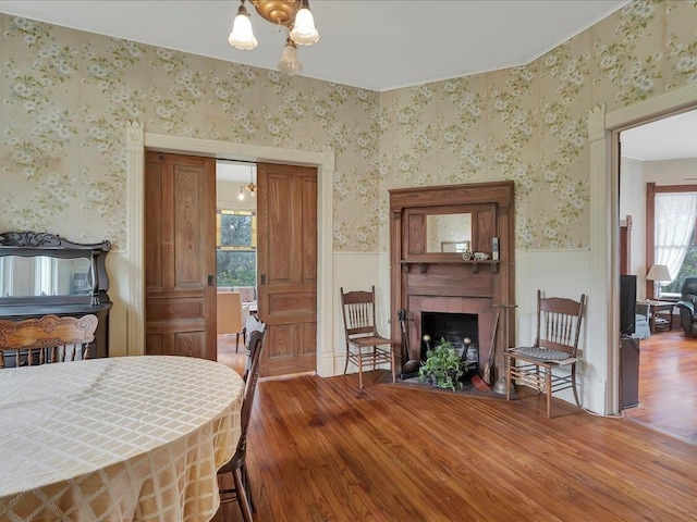 dining area featuring a tile fireplace, wood-type flooring, and a notable chandelier