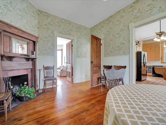 bedroom with black refrigerator, light hardwood / wood-style flooring, and a fireplace