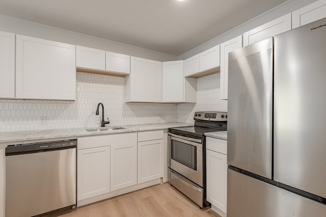 1311 Walnut Bend Dr, Lufkin, TX 75904 - kitchen with stainless steel appliances, white cabinets, light countertops, tasteful backsplash, and light wood-style floors
