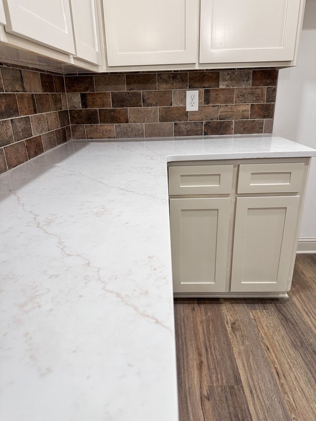 4 Columbia Ct, Lufkin, TX 75901 - detailed view of backsplash, dark wood-type flooring, light stone counters, and white cabinets