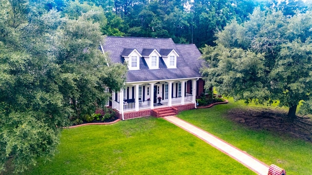 703 Shady Ln, Diboll, TX 75941 - cape cod house featuring a porch and a front yard