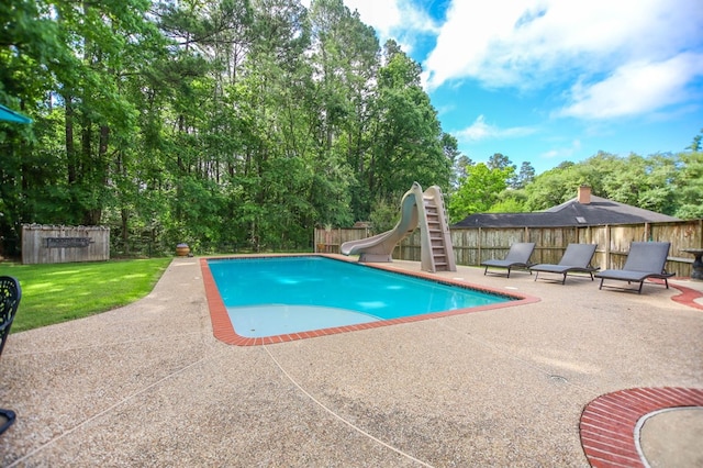 703 Shady Ln, Diboll, TX 75941 - view of swimming pool featuring a water slide, a patio, and view of wooded area