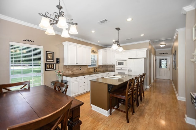 703 Shady Ln, Diboll, TX 75941 - kitchen featuring white appliances, a sink, white cabinets, a breakfast bar, and tasteful backsplash