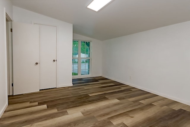 unfurnished bedroom with baseboards, wood finished floors, and vaulted ceiling