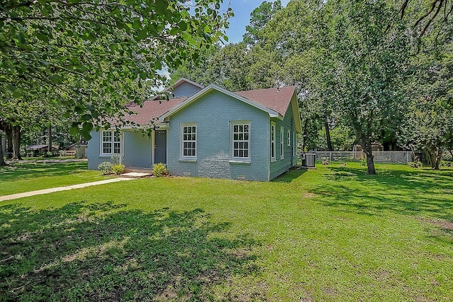 view of front of home featuring central AC, fence, and a front yard