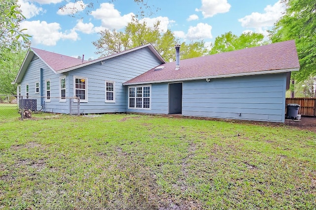 rear view of property with a lawn and fence