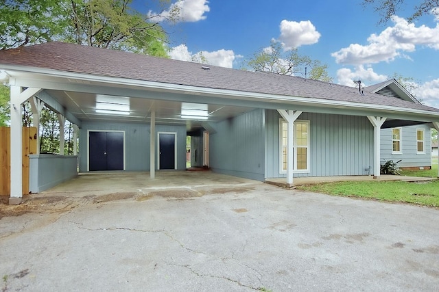 ranch-style home featuring aphalt driveway, roof with shingles, and an attached carport